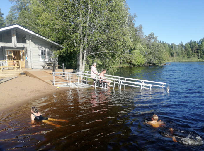 Uutta veteen vievää ramppia kokeilee uudella suihkupyörätuolilla Jari Kiveinen avustajanaan Heidi Lähteenmäki.